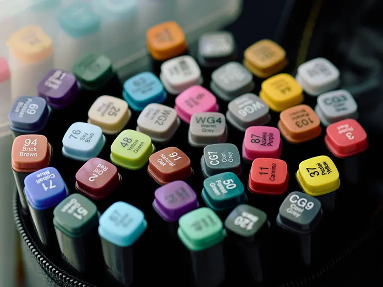 Colorful acrylic paint marker caps arranged across a black zip binder cover